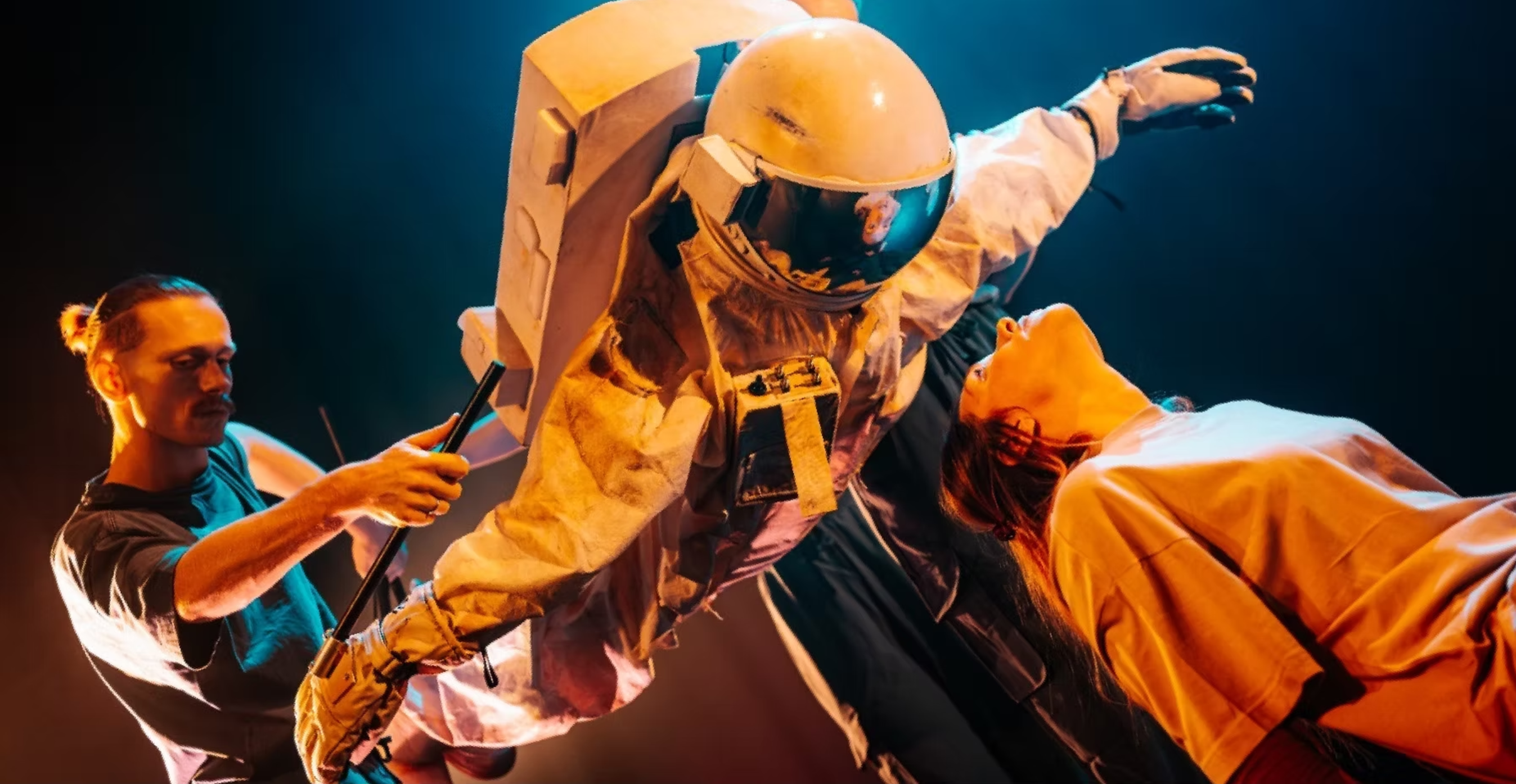 A life-size puppeteered spacesuit floats over a woman, who looks into its visor.